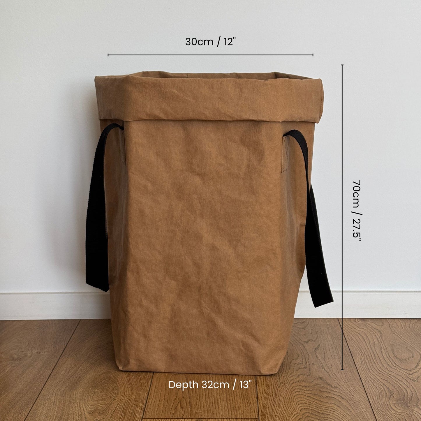 Brown paper laundry bag with black straps and measurements on a wooden floor.