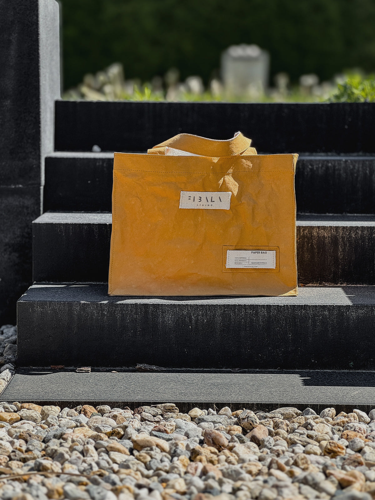 Mustard yellow washable paper carry-all bag on concrete steps, close-up front view — Fibala Living L size