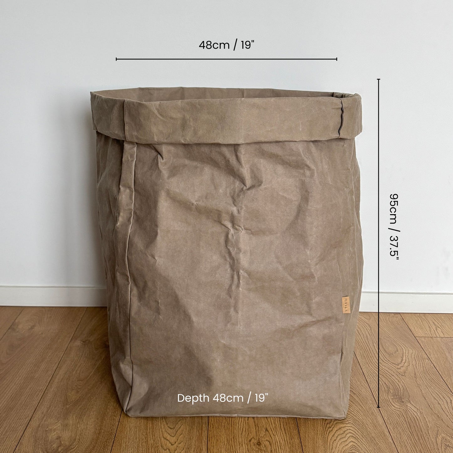 Giant washable paper bag with dimensions on a wooden floor and white wall background