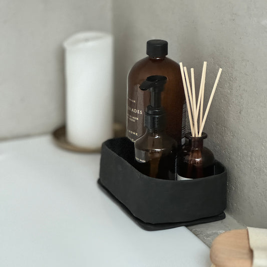 Black medium washable paper tray holding bottle & sticks, textured wall backdrop, eco chic organizer