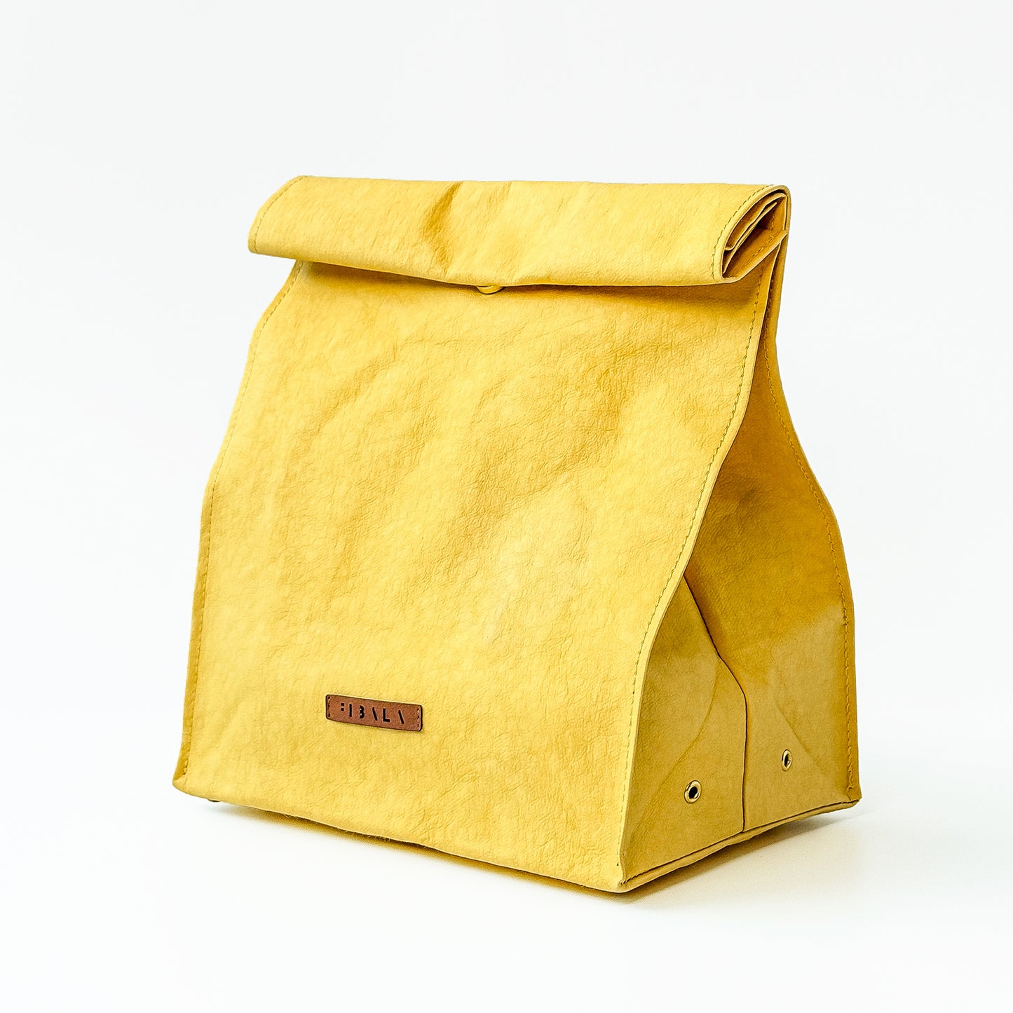 Minimalist yellow washable paper lunch bag with folded top and metal snap closure, shown standing upright on a white background.