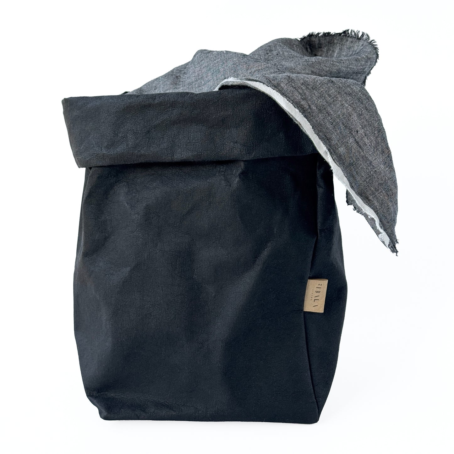 Extra-large black washable paper bag, showcasing versatility with linen throw inside, featuring a visible brand tag, on a white background | Reusable, eco-friendly storage solution