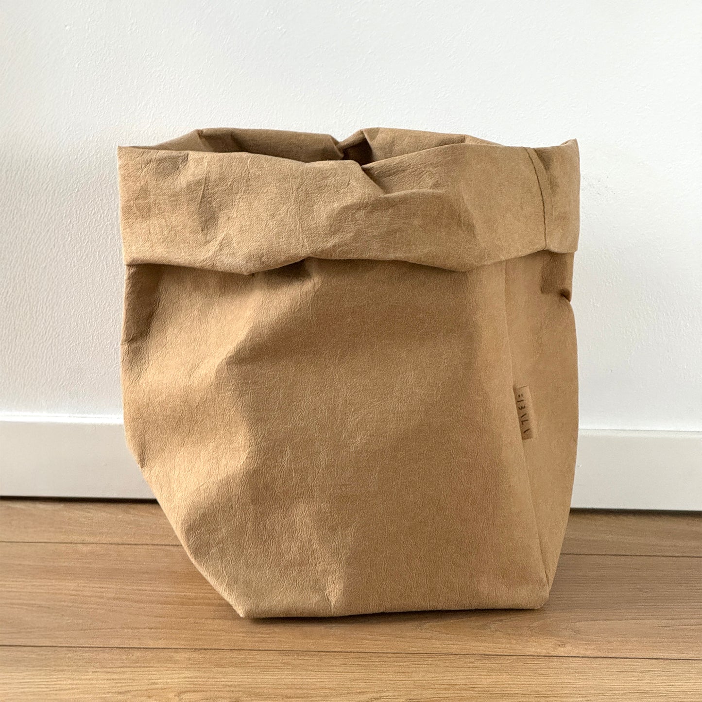 Extra-large brown washable paper bag on wooden floor, white wall background | Reusable eco-friendly bag