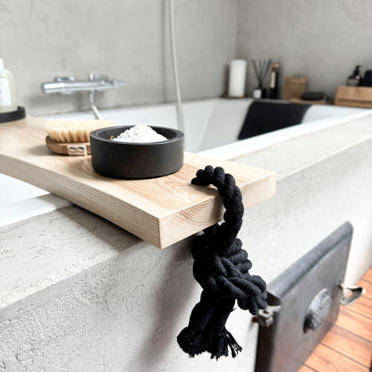 Live-edge ash wood bath caddy, black cotton rope, holds spa essentials on tub rim - close up