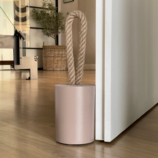 Concrete door stop with a natural jute handle in earthy Desert Taupe Brown, positioned next to an open door. The close-up highlights the textured concrete surface, with a modern, earthy-toned interior in the background. A perfect accent for contemporary rustic, farmhouse, boho, coastal, or minimalist Scandinavian-style interiors.