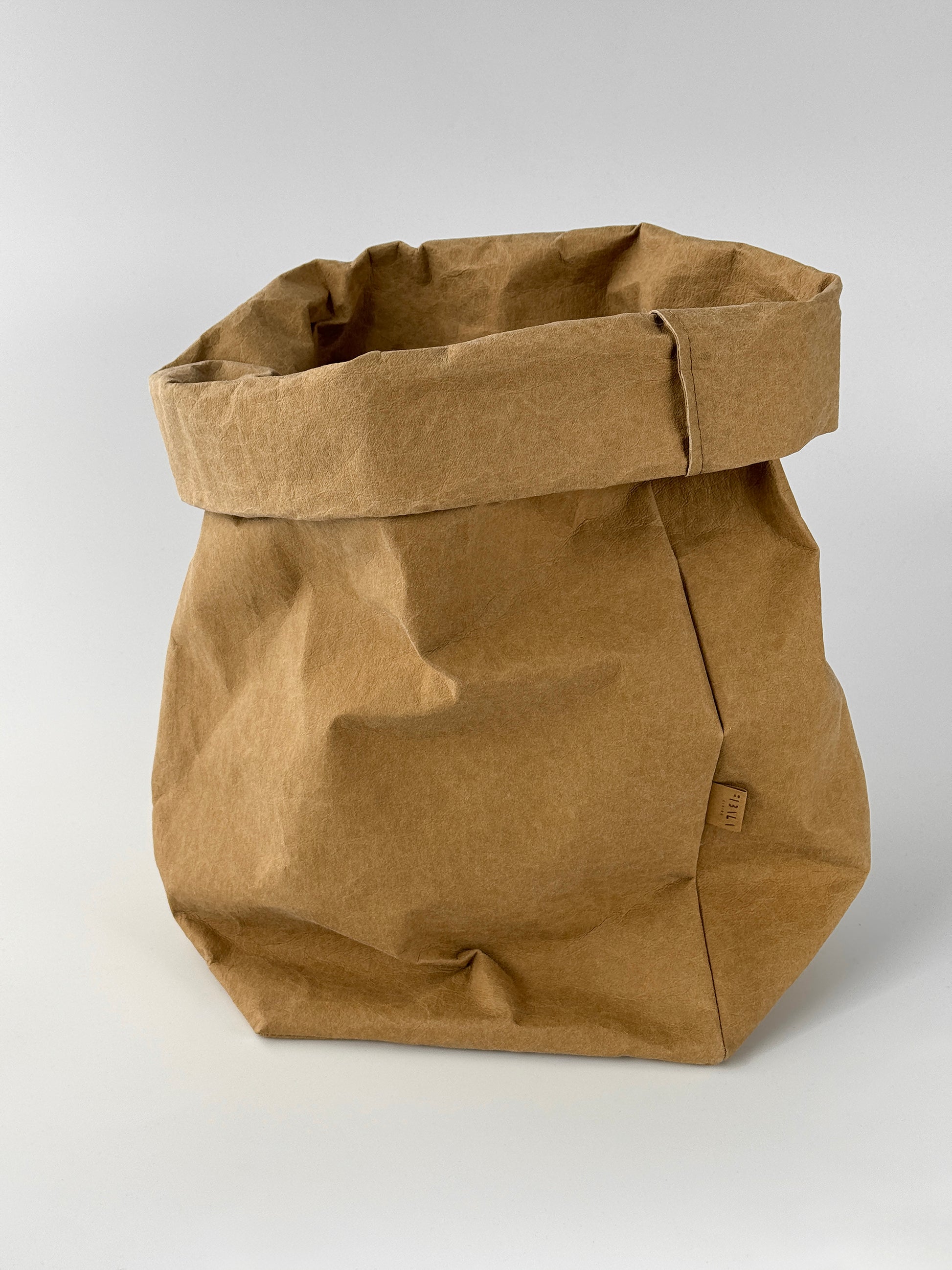 Oversized  brown washable paper bag with a rolled top edge, studio shot on light gray background