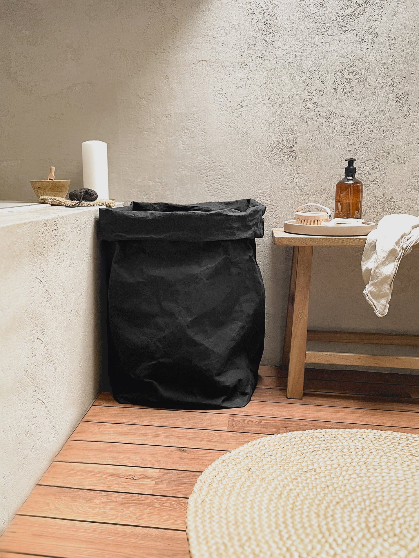 Black washable paper bag used as a laundry hamper, wooden floor bathroom setting