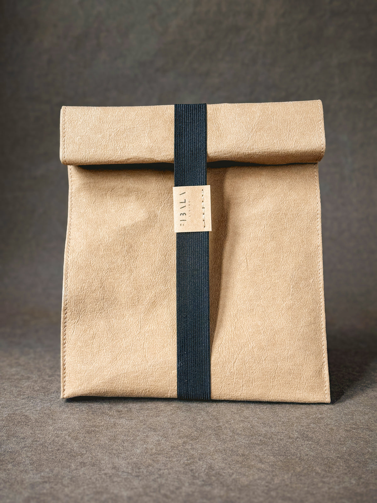 Brown washable paper lunch bag with the top rolled down, closed with a black elastic band and Fibala Living label