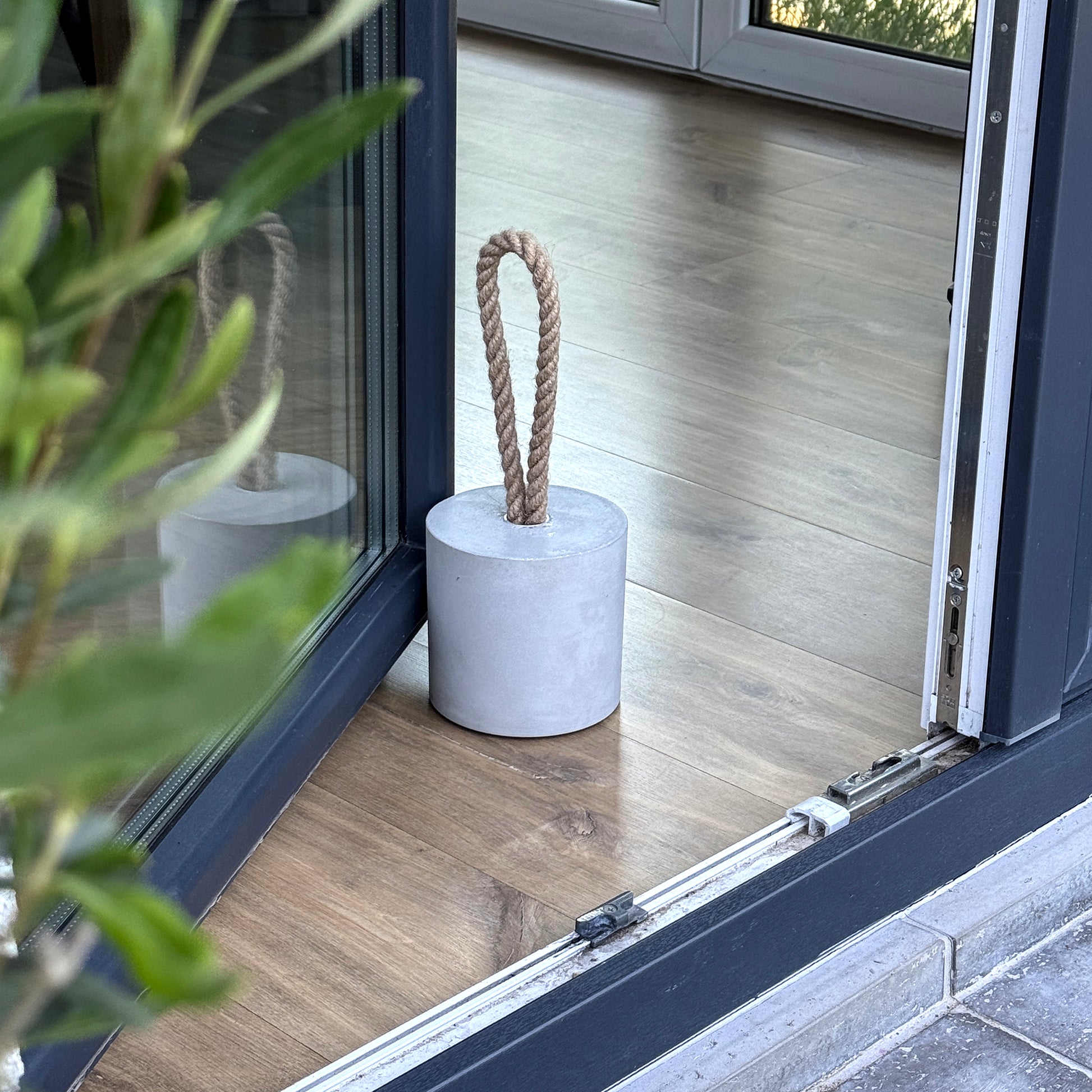 Minimalist concrete door stop with rope handle on floor
