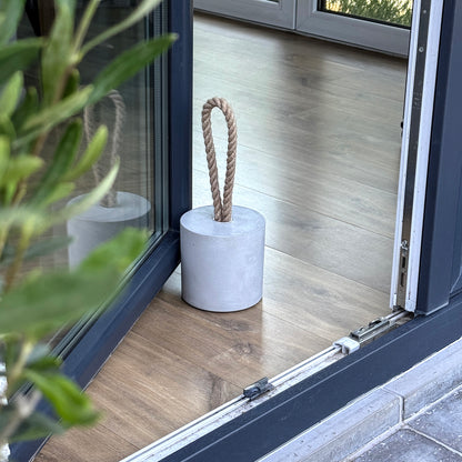 Minimalist concrete door stop with rope handle on floor