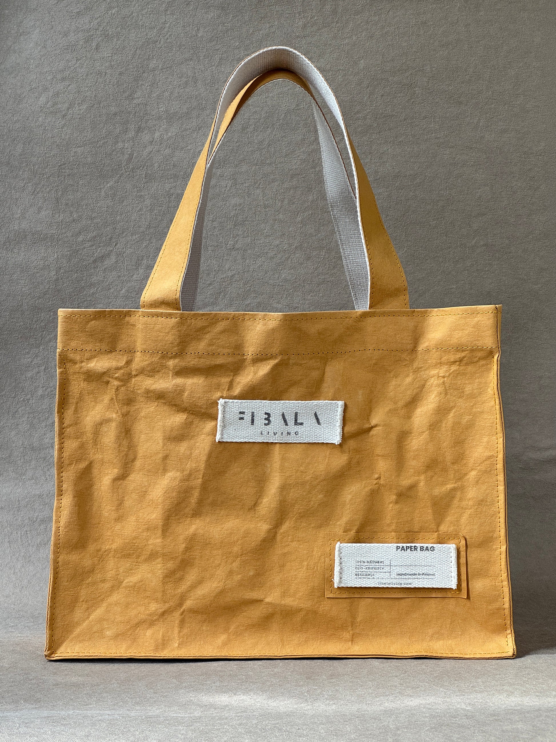 Mustard yellow washable paper carry-all bag against a neutral gray background — product shot, Fibala Living L size