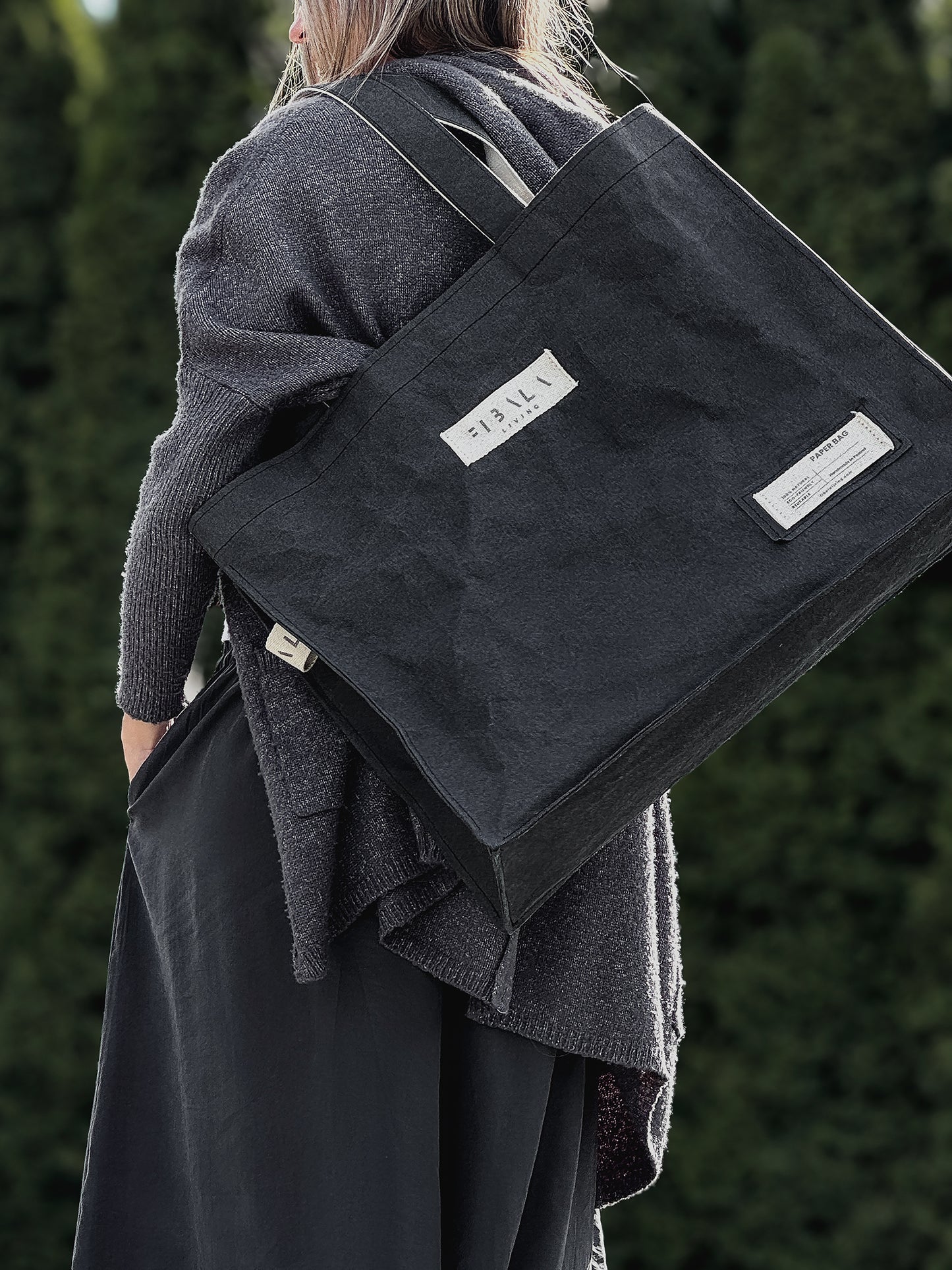 Black Fibala carry-all bag on shoulder, close-up side view showing cotton logo patch — XL size