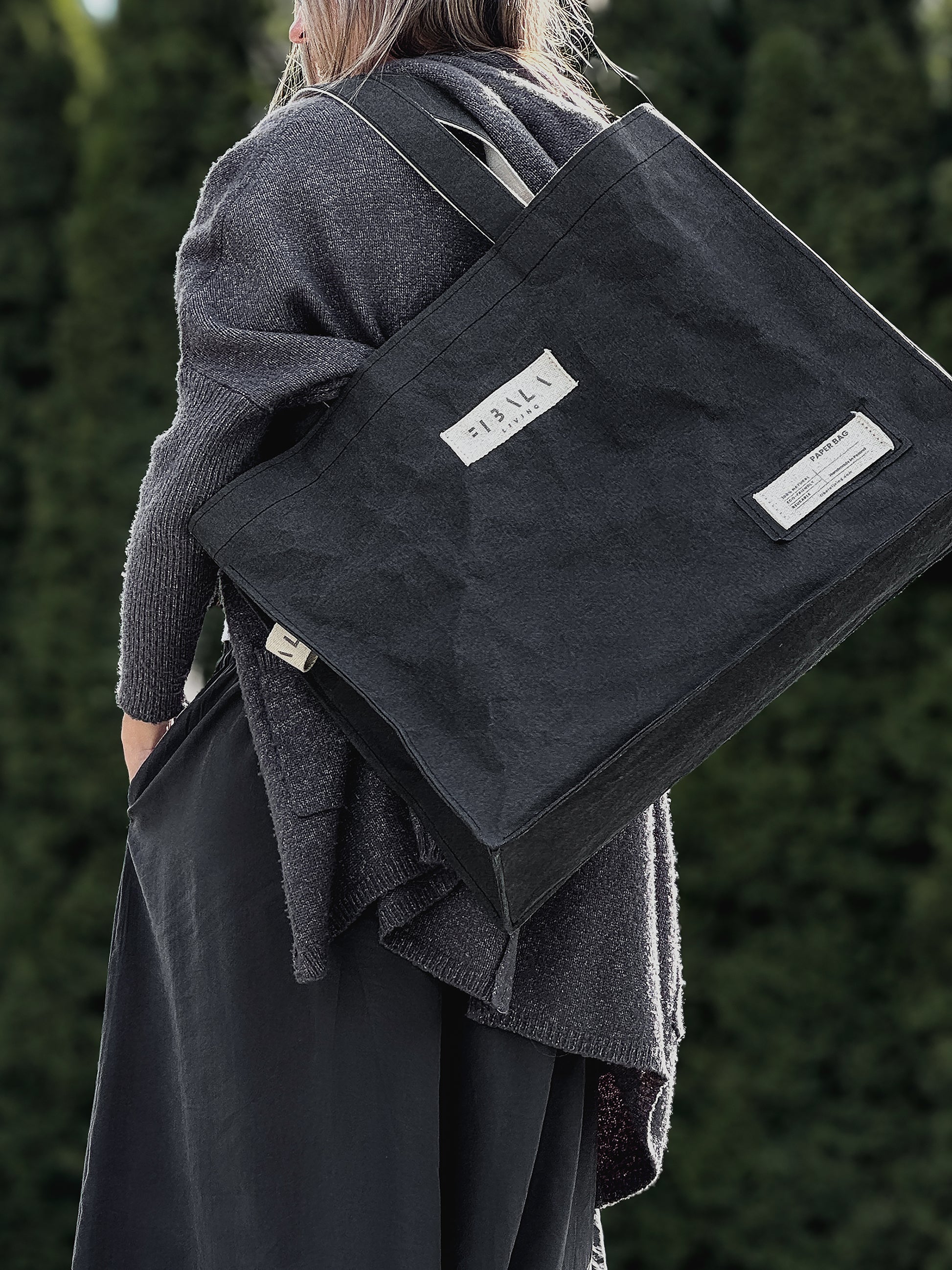 Black Fibala carry-all bag on shoulder, close-up side view showing cotton logo patch — XL size
