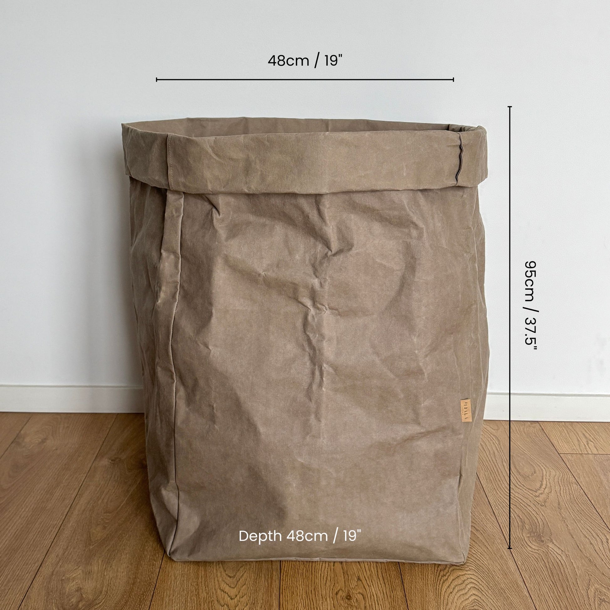 Giant washable paper bag with dimensions on a wooden floor and white wall background