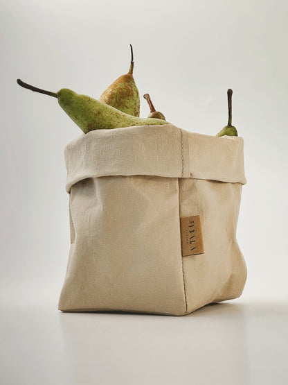 Small beige washable paper bag filled with fresh pears photographed on white background