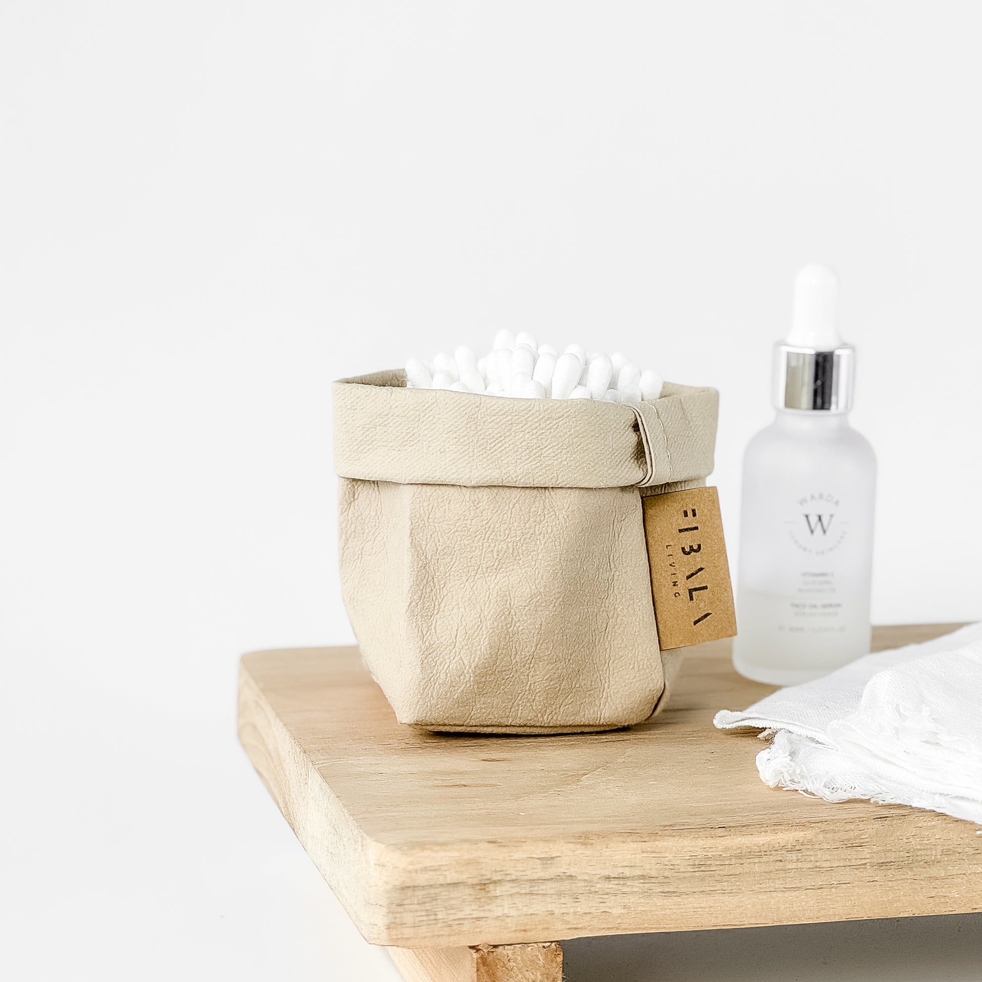 Mini sand beige washable paper bag, white earbuds, wood surface—eco chic mini tote