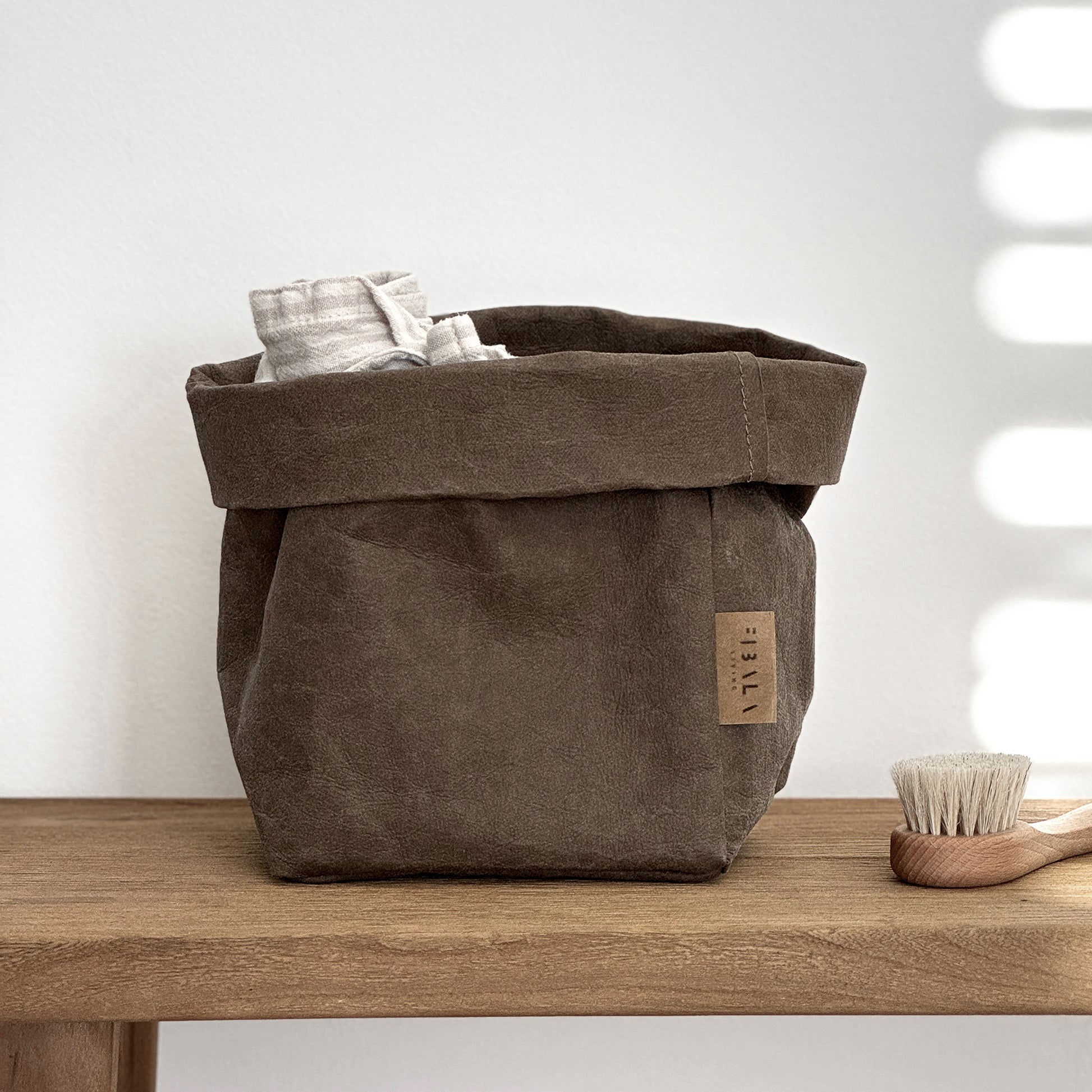Small Brown Washable Paper Bag Basket on Wooden Surface with Blurred Background