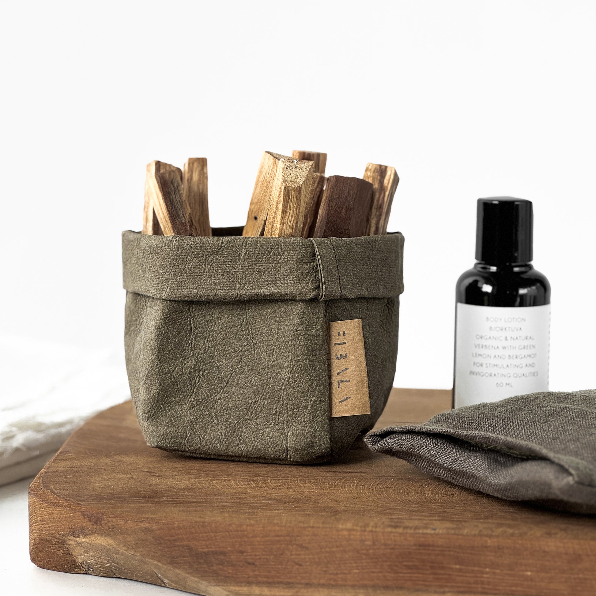 XS olive-green washable paper bag, wooden sandal sticks, bottle, towel, wood surface—eco mini tote