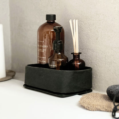 Side-view black medium washable paper tray, bottle & sticks, textured wall, slim eco organizer
