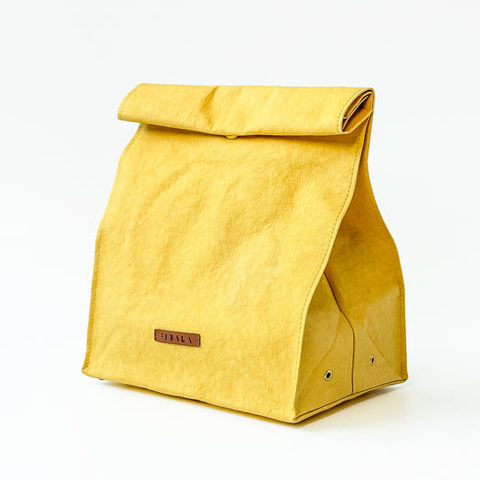 Minimalist yellow washable paper lunch bag with folded top and metal snap closure, shown standing upright on a white background.