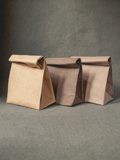 Three washable paper lunch bags in warm brown tones with rolled tops