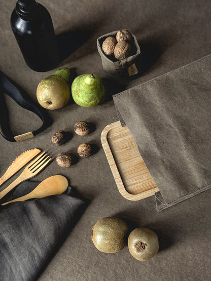 Packed lunch flat lay with a washable paper lunch bag, bamboo lunch box, fruit and wooden cutlery