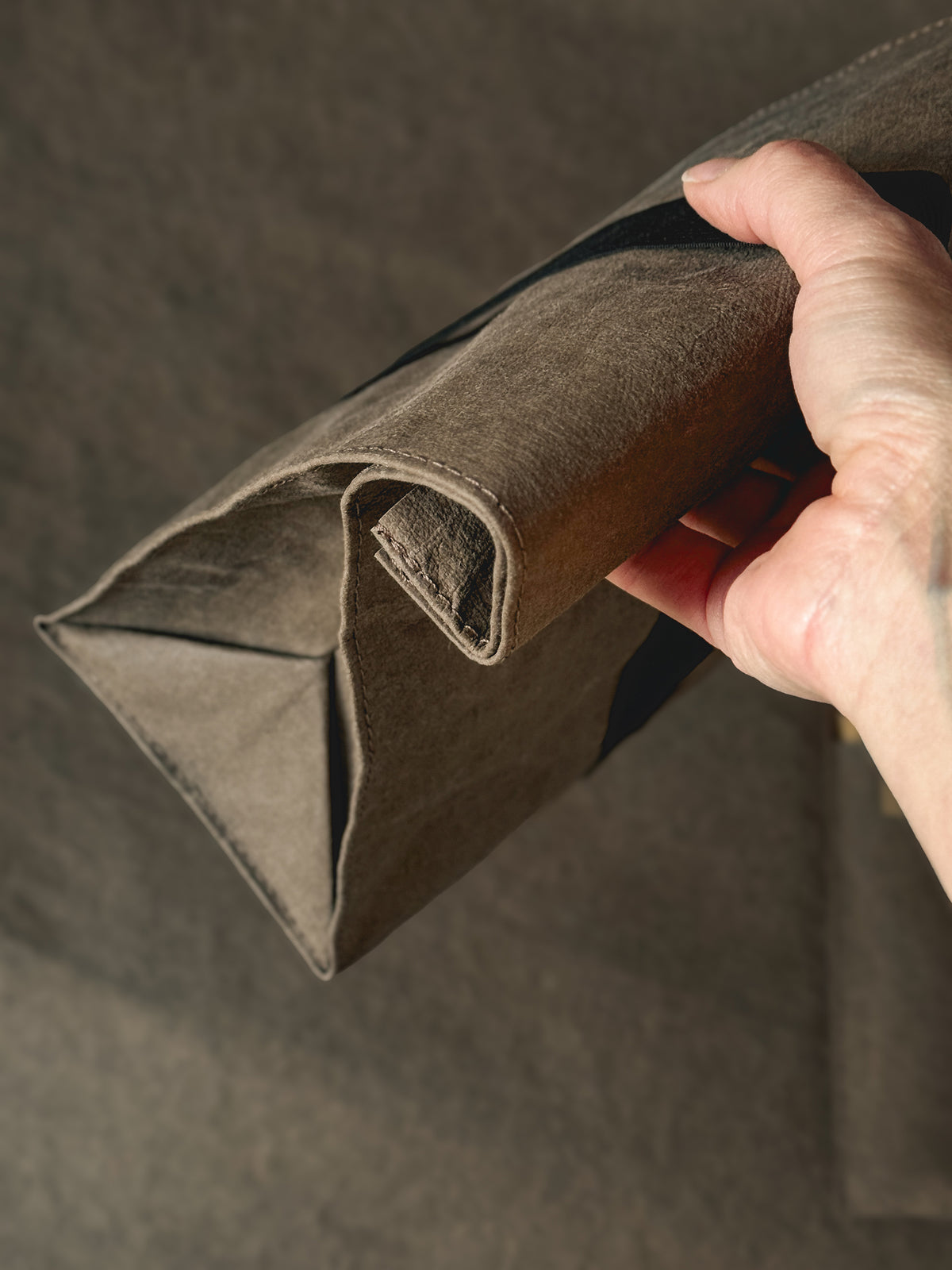 Hand rolling down the top of a washable paper lunch bag
