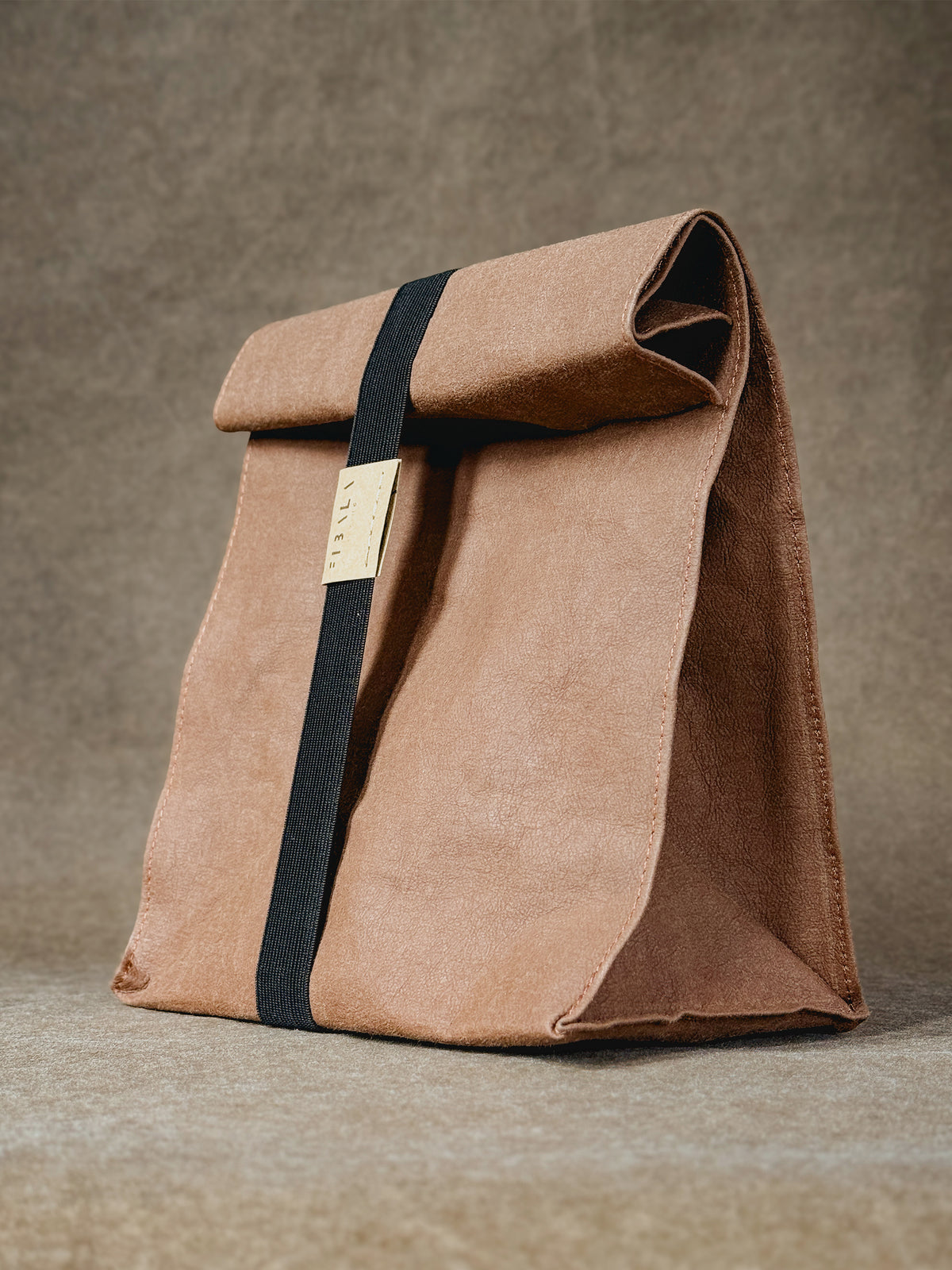 Warm brown washable paper lunch bag closed with a black elastic band and Fibala Living label