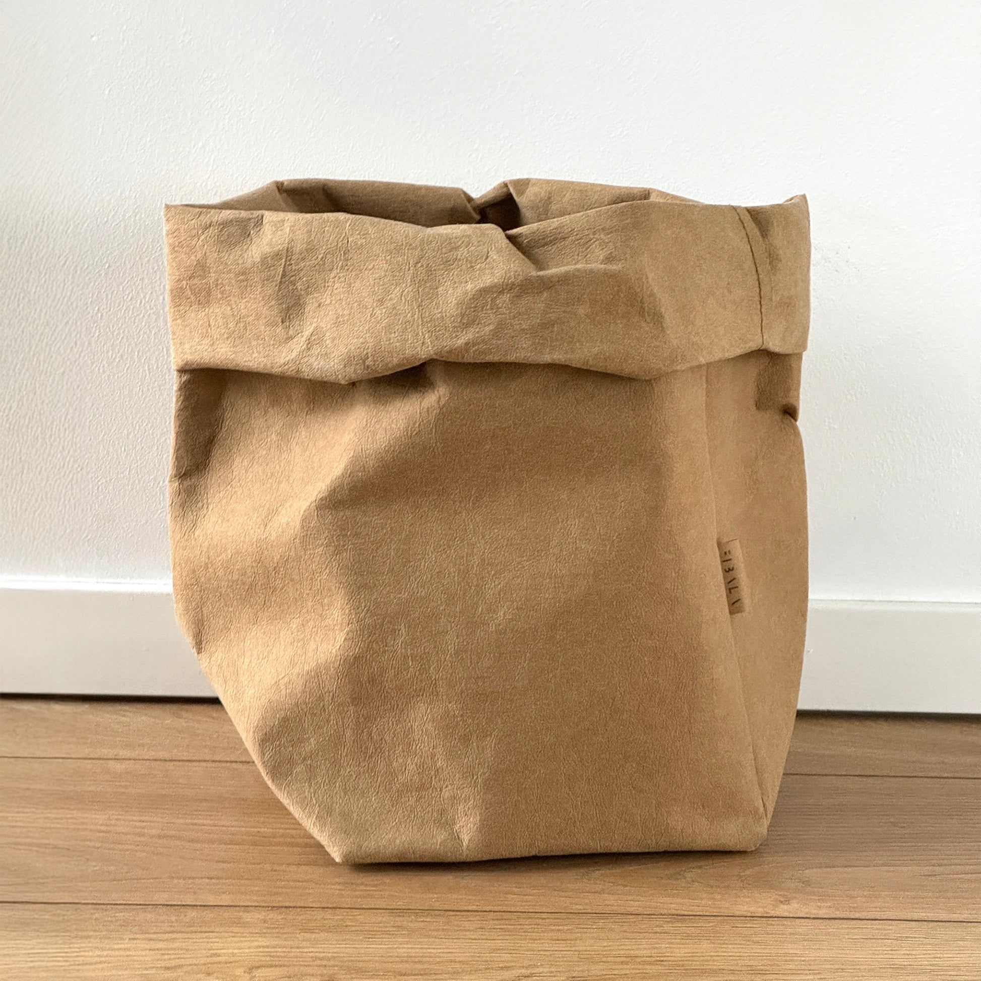 Extra-large brown washable paper bag on wooden floor, white wall background | Reusable eco-friendly bag