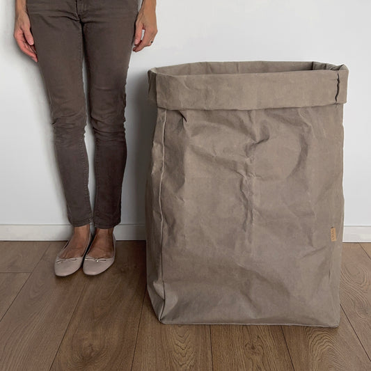 Person standing next to a giant chino washable paper bag on a wooden floor.