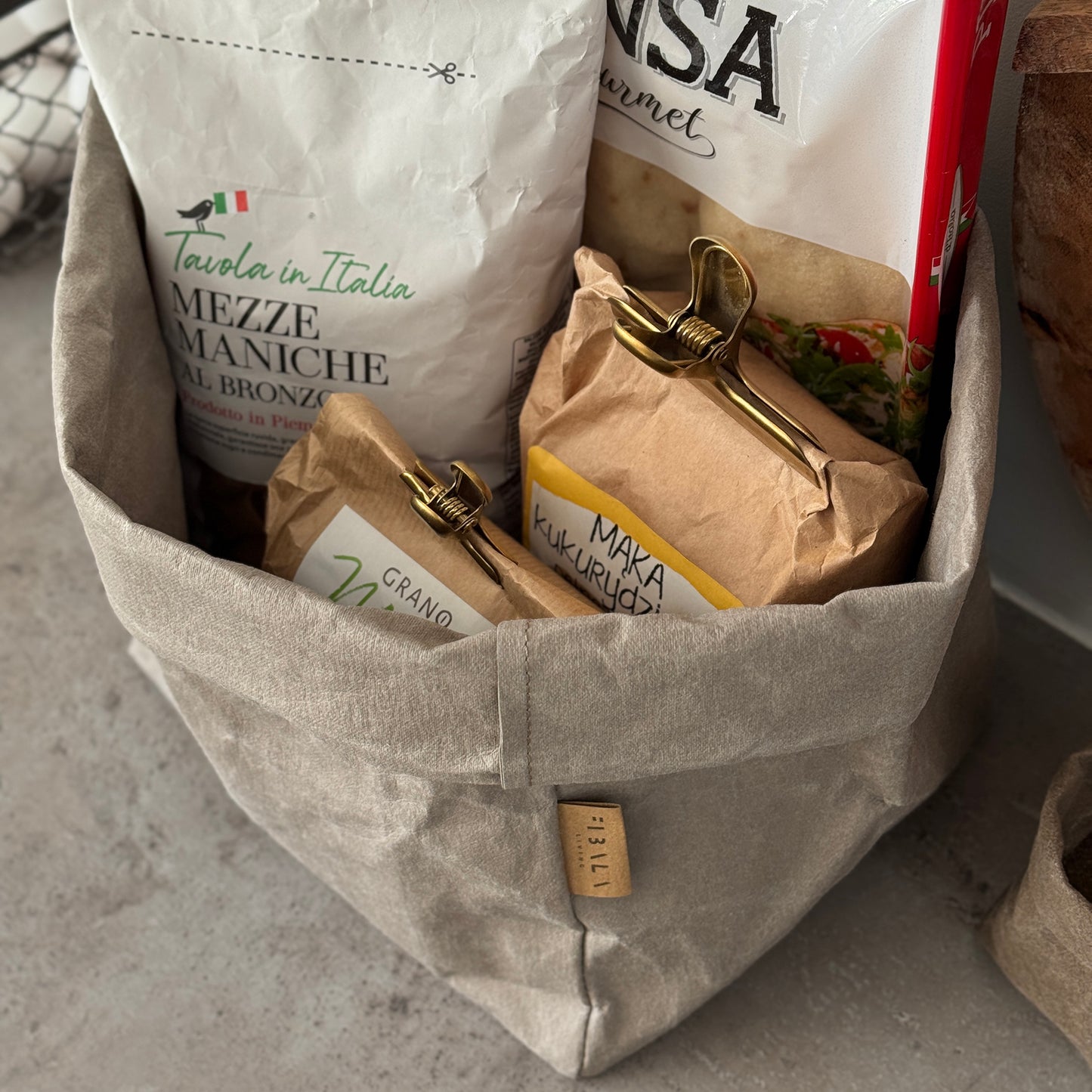 Large washable paper bag filled with pasta and flour bags on a concrete counter