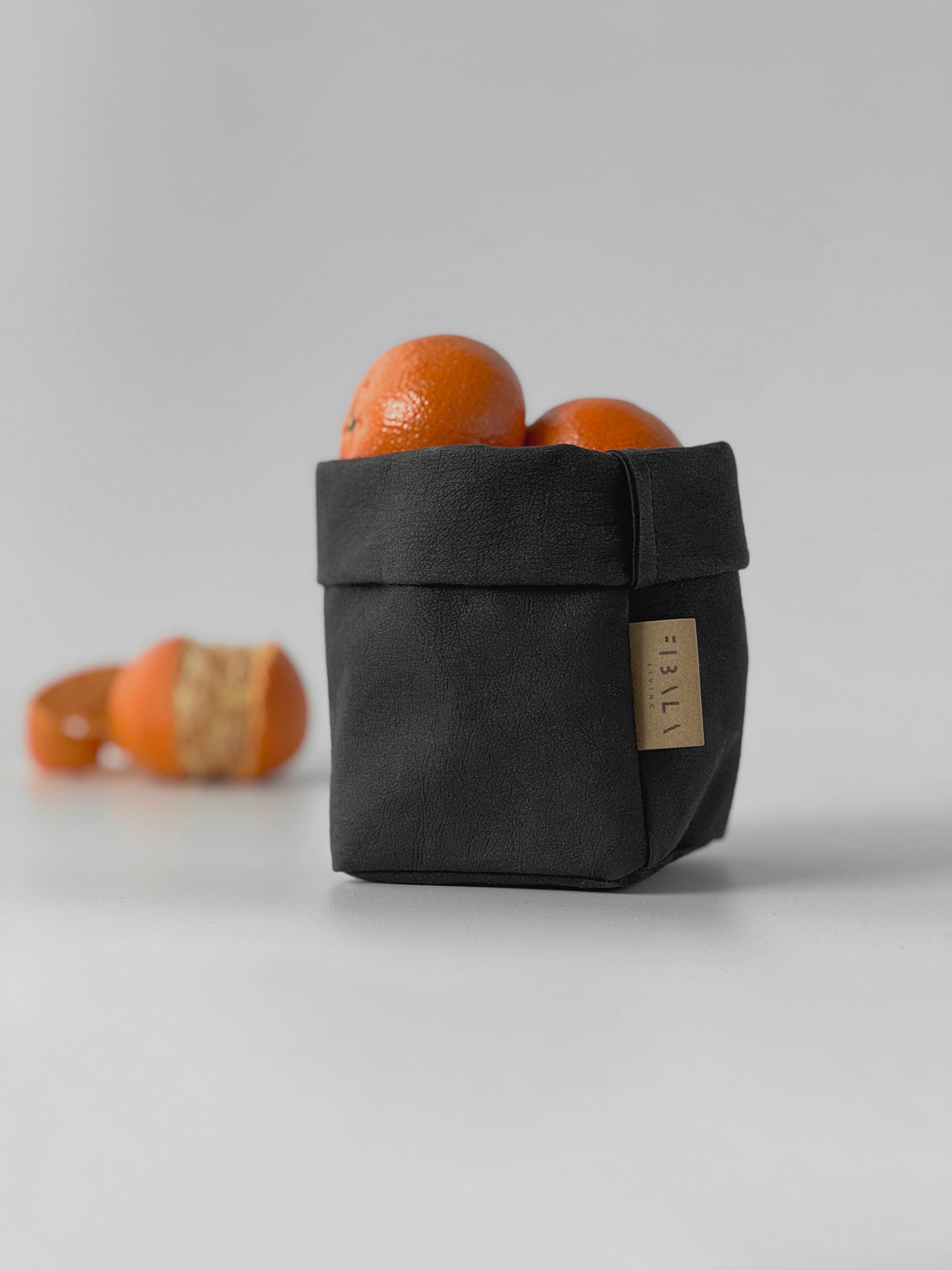 Black washable paper bag with mandarines on a light gray background