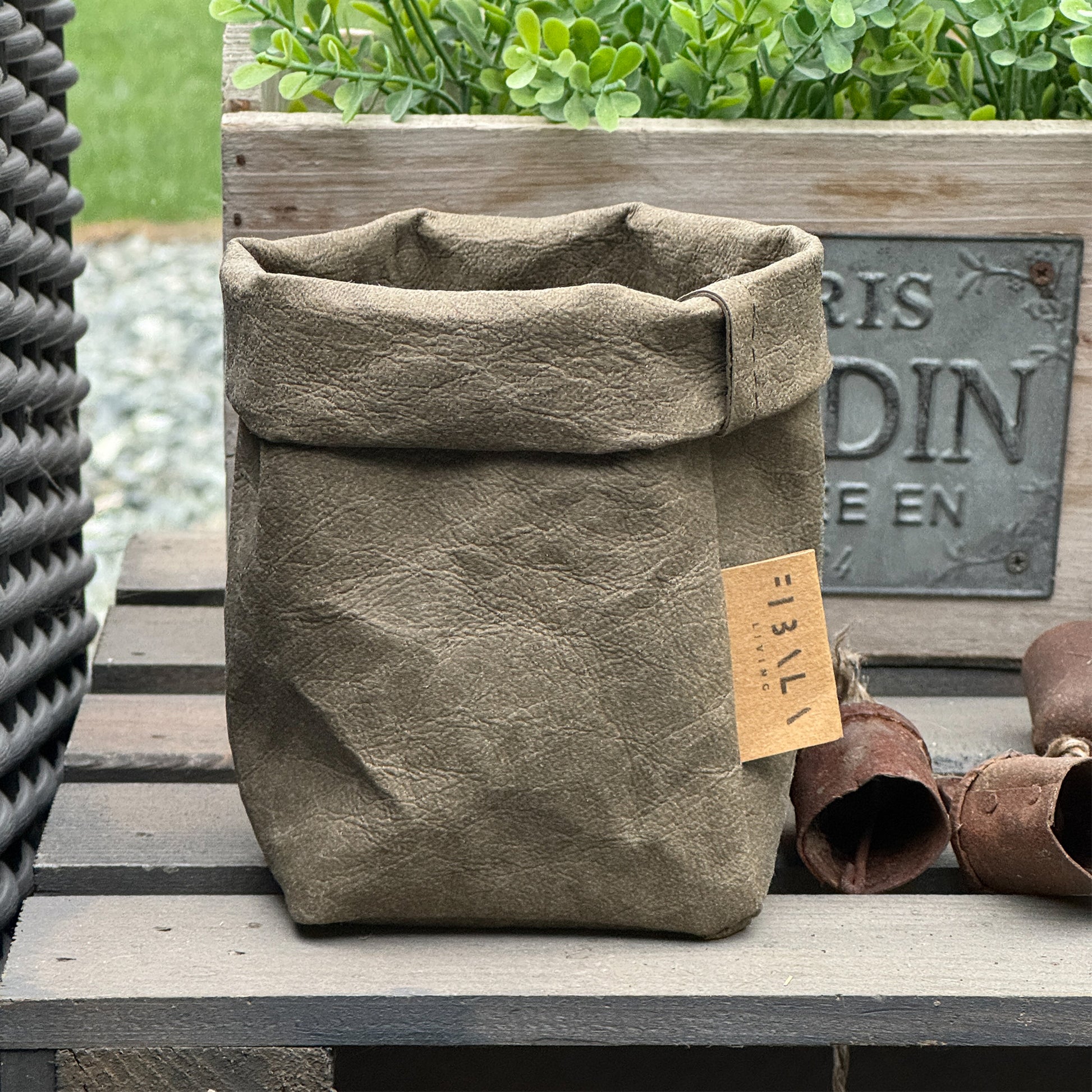 Petite olive-green washable paper planter with tag on wooden surface outdoors—eco mini planter tote