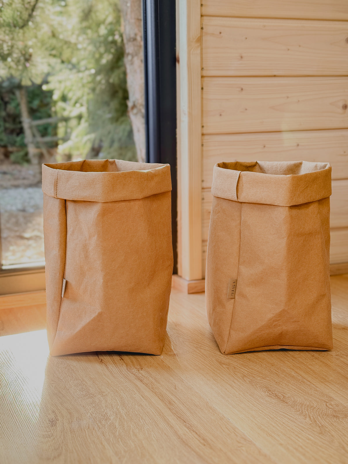 Two XL washable paper storage bags side by side by a window