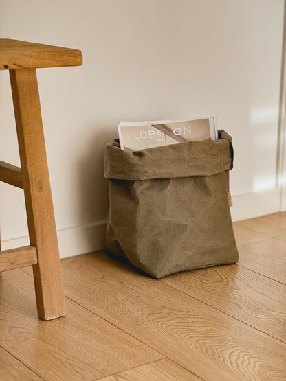 XL washable paper storage bag holding magazines beside a wooden stool