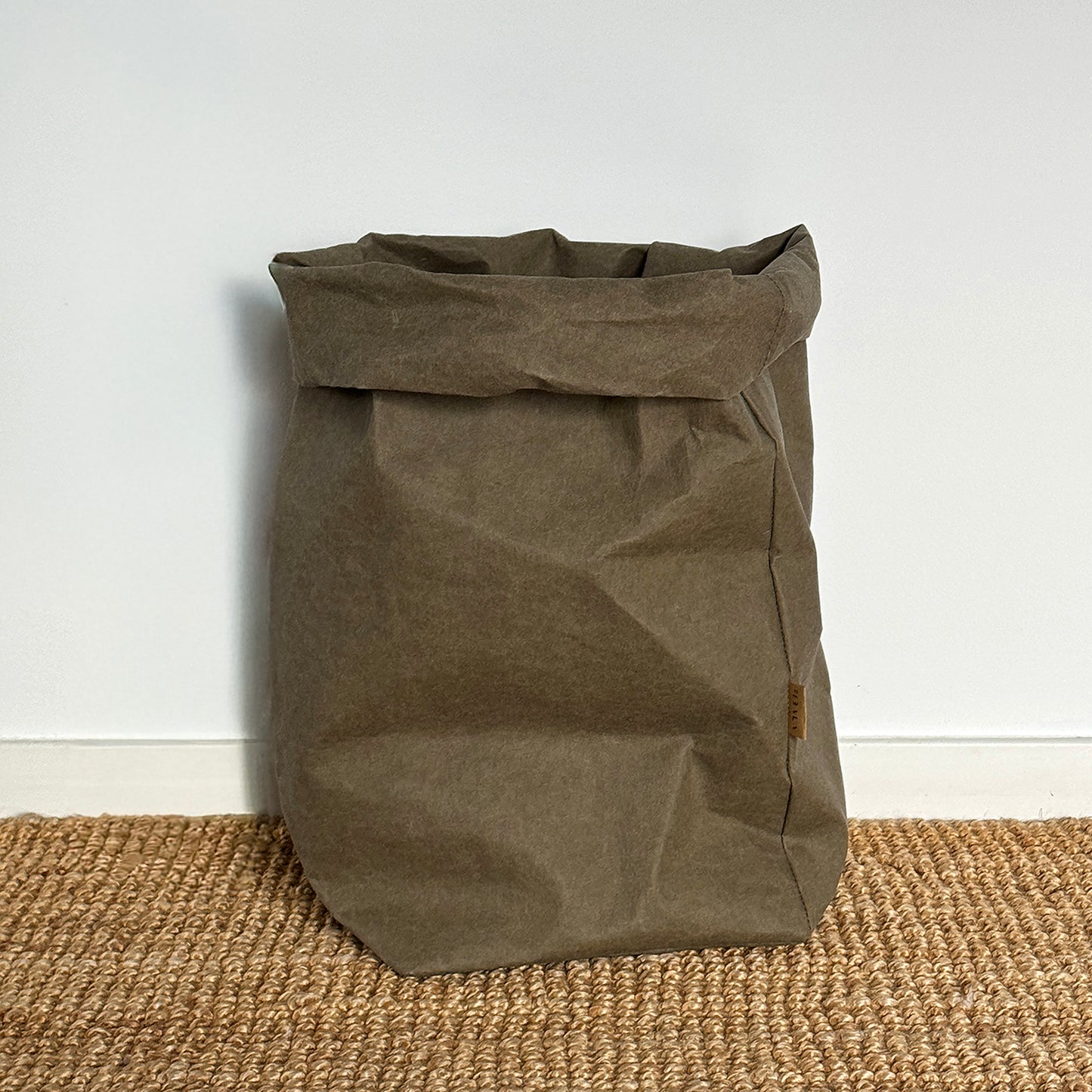 XXL olive-green washable paper bag, textured floor, white wall, eco reusable storage