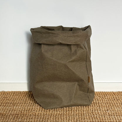 XXL olive-green washable paper bag, textured floor, white wall, eco reusable storage